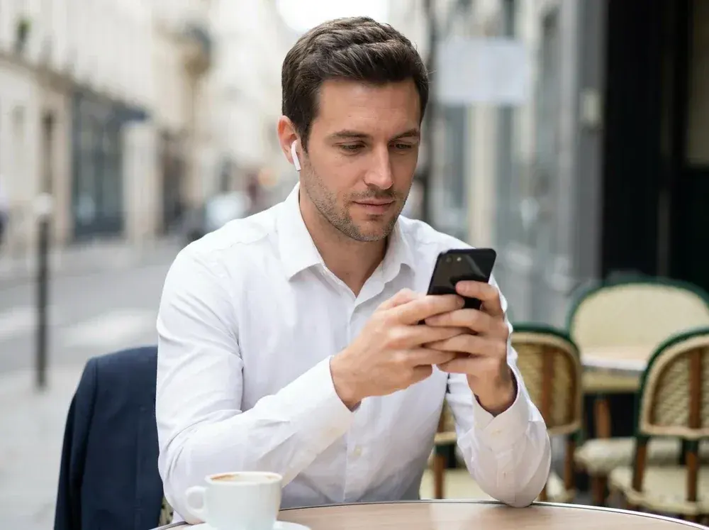 Homme consultant son téléphone à la terrasse d'un café