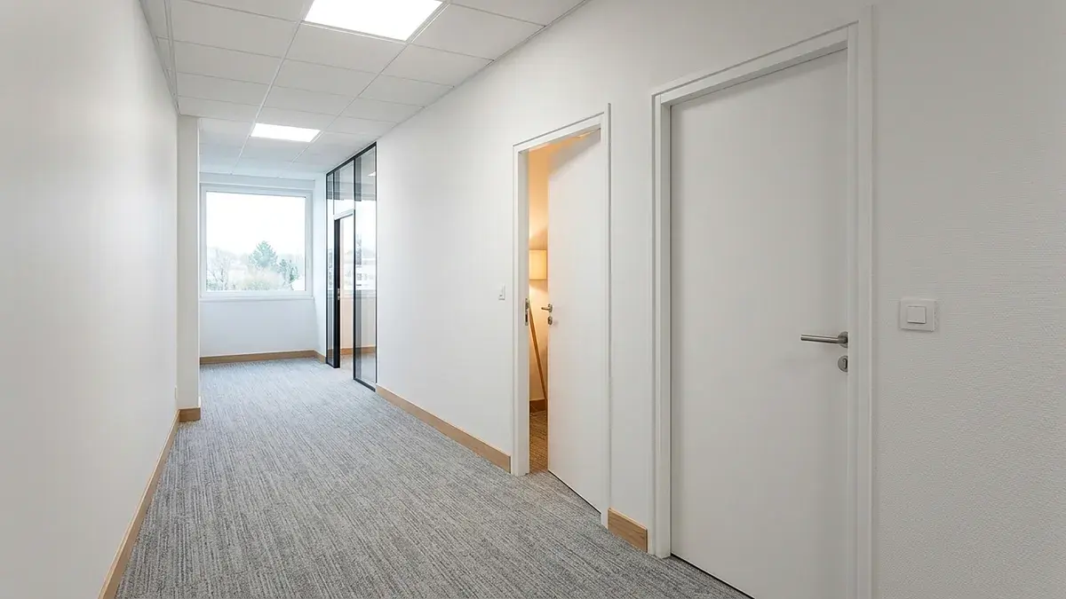 Couloir de bureaux blanc avec deux portes ouvertes